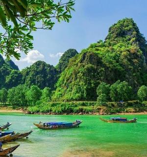 a group of boats in the water near a mountain