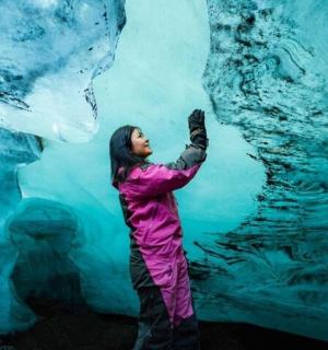 a woman is standing in front of an iceberg