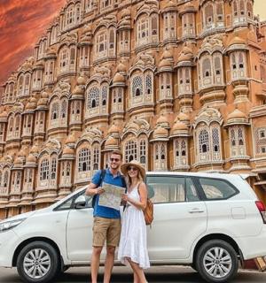 a man and a woman standing in front of a white car