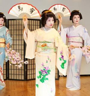 three women in kimonos are holding umbrellas