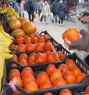 a person holding up oranges in baskets in a market