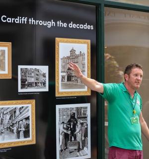 一名男子站在挂满图画的墙前