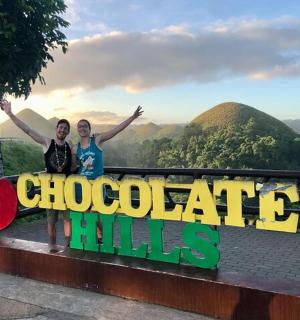 two women standing behind a sign that reads chocolate hills