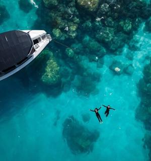 two people swimming in the ocean next to a boat