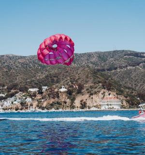 a pink kite flying over a boat in the water