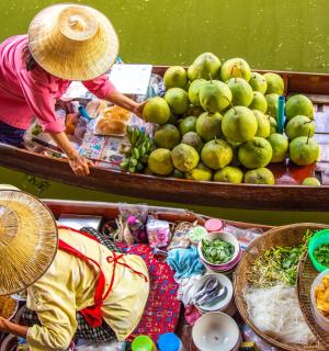 two women in hats on a boat with fruits and vegetables