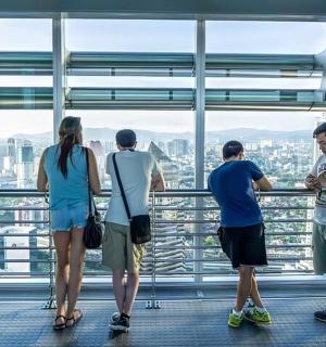 skupina lidí dívajících se na město z vyhlídkové plošiny