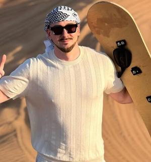 一名男子手持滑板,竖起大拇指