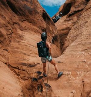 a man walking through a slot canyon in a canyonlands