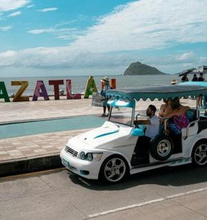 a golf cart parked next to the beach with people in it
