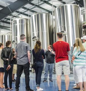 a group of people standing around in a brewery