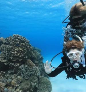 一个人在水中，拿着相机站在礁石上