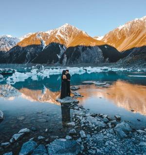 一位女子站在水体中,远处是群山。