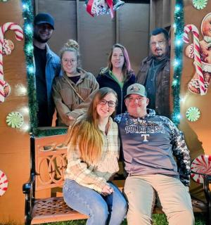 skupina lidí pózujících před perníkovou chaloupkou