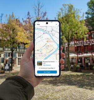 žmogus, laikantis mobilųjį telefoną su žemėlapiu