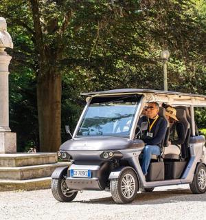 一名男子驾驶高尔夫球车行驶在一座雕像前。