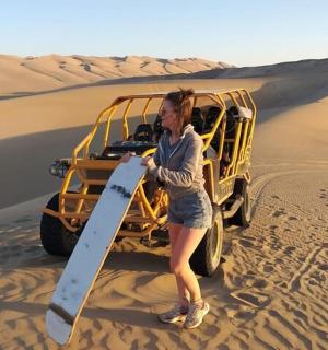 一名女子站在沙漠中的一辆车前