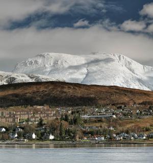一座白雪皑皑的山,山上有一座小镇,前面是一座城市