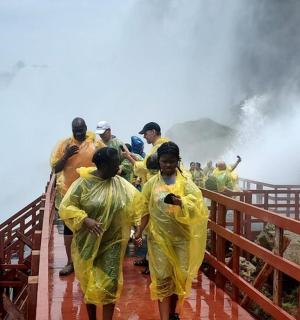 Skupina lidí v žlutých pláštěnkách kráčejících po mostě