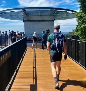 a man walking on a bridge with a backpack