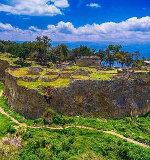 山顶上有一座古老的城堡，周围环绕着草地和树木。