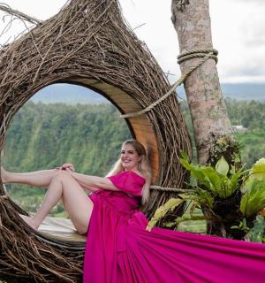 a woman in a pink dress sitting in a hanging chair