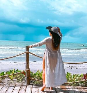 一位身穿白色连衣裙的女子站在海滩上