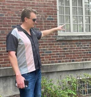 muž ukazující na okno cihlové budovy