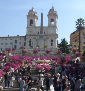 skupina lidí stojící před budovou s květinami