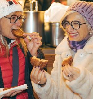 two women are eating food in their hands