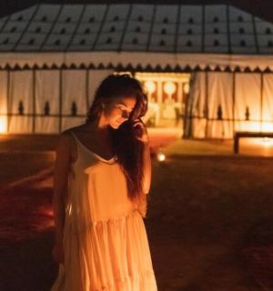 一位身穿白色连衣裙的女子站在一栋建筑前