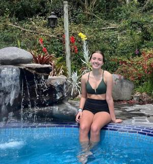 一位女士坐在喷泉旁的游泳池里。