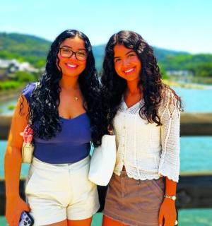 two women standing next to each other near the water