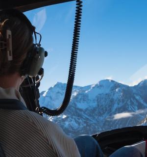 a person sitting in a seat looking out a window at mountains