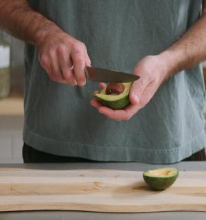 一名男子在砧板上用刀切牛油果
