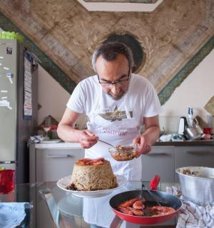 a man in a kitchen cutting a cake