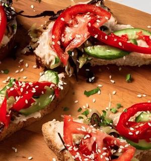 a wooden cutting board with sandwiches with peppers on it