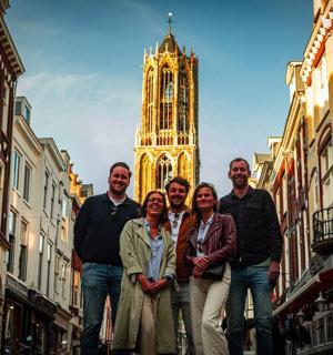 a group of people standing in a street with a clock tower