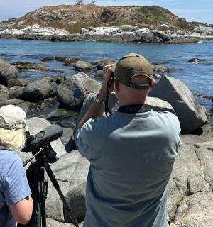 seorang lelaki dan wanita berdiri di atas batu berhampiran air