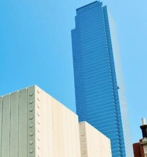 en høj skyskraber står ved siden af to bygninger