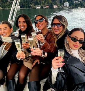 กลุ่มผู้หญิงนั่งอยู่บนเรือพร้อมแก้วแชมเปญ