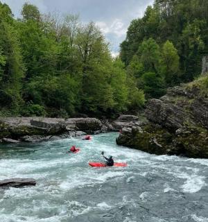 zwei Personen in Kajaks auf einem Fluss mit Stromschnellen
