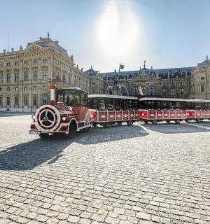 ein roter Zug vor einem großen Gebäude