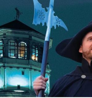 ein als Zauberer verkleideter Mann, der eine Flagge vor einem Turm hält