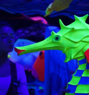 une femme debout à côté d'un jouet dinosaure vert