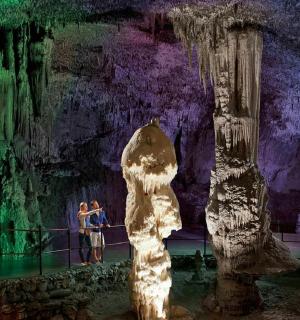 група људи стоји испред пећине