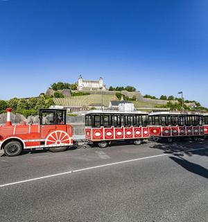 ein roter Zug, der eine Straße neben einer Straße entlangfährt