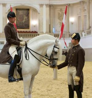 ชายในเครื่องแบบกำลังนั่งอยู่บนหลังม้าสีขาว