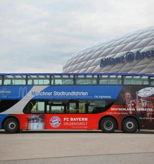 a double decker bus parked in front of a stadium