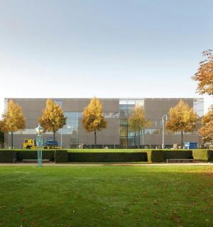 ein großes Gebäude mit Bäumen vor einem Park